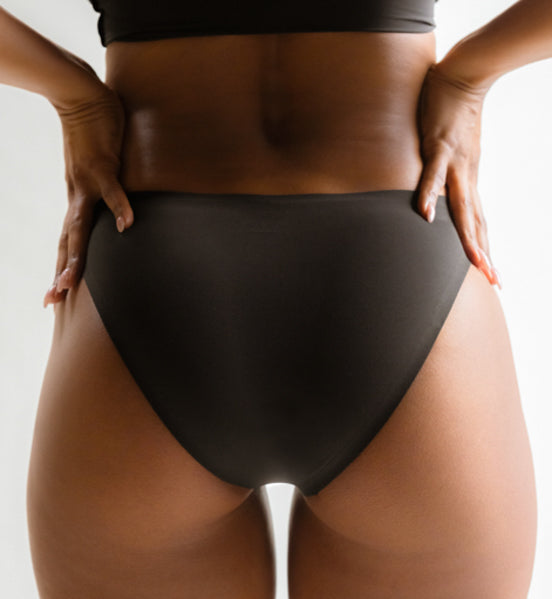 Rear view of a model wearing Pretty Kitty Klub Briefkini in Kitty Noir black, showing the fit and back coverage.